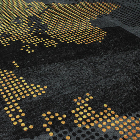 Esquina de la alfombra 'Mundo', mostrando el patrón dorado de mapas del mundo y el elegante fondo gris. Esta alfombra moderna añade un toque cosmopolita a cualquier habitación y es lavable en lavadora para un cuidado conveniente.