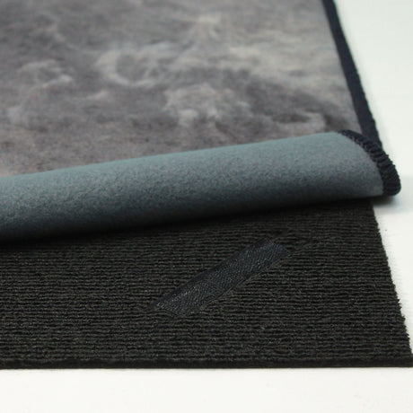 Vista completa del frente y reverso de la alfombra 'Prestige', resaltando su diseño abstracto en tonos grises y dorados. La base antideslizante y el diseño lavable en lavadora combinan estilo con funcionalidad.